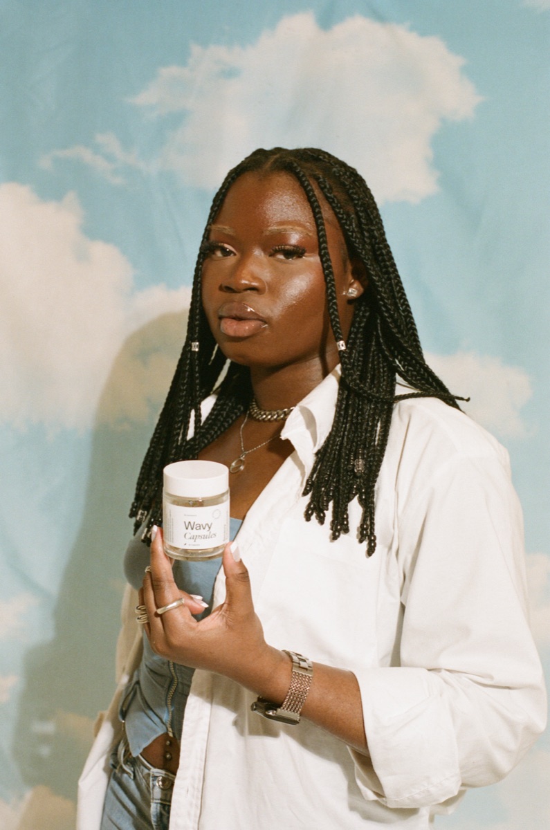 mgx wavy jar sky - Blog A woman in warm film light holds a jar of Microgenix Wavy capsules against a soft sky and clouds backdrop, calm and reflective