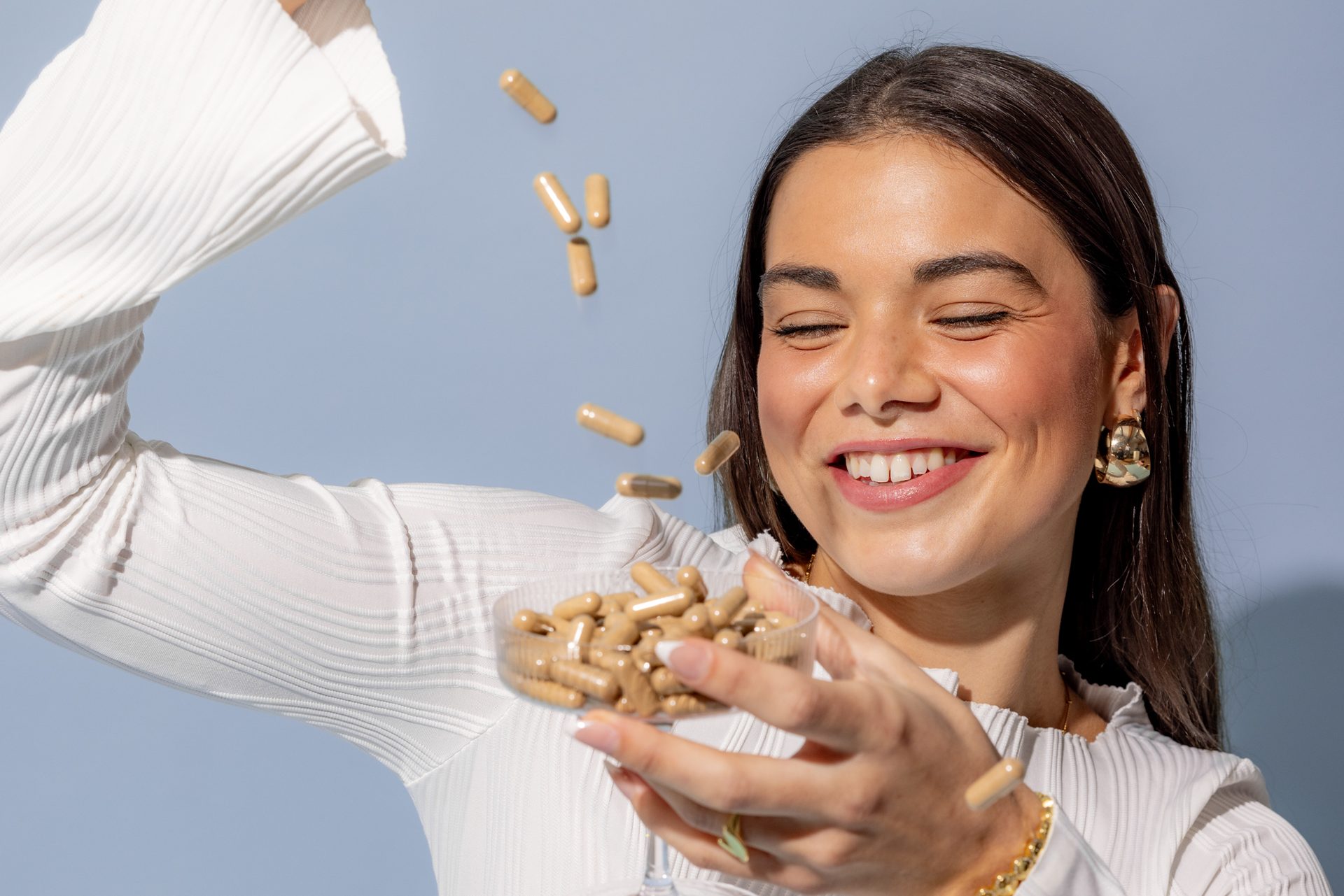 Smiling woman tossing Microgenix capsules from a glass dish