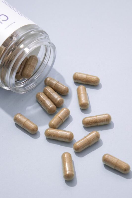 microdosing cost capsules - Blog Microgenix Clarity capsules spilling from an open glass jar onto a pale blue surface