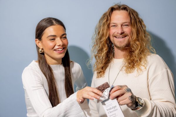 Two people laughing while unwrapping a Microgenix Indulge chocolate bar