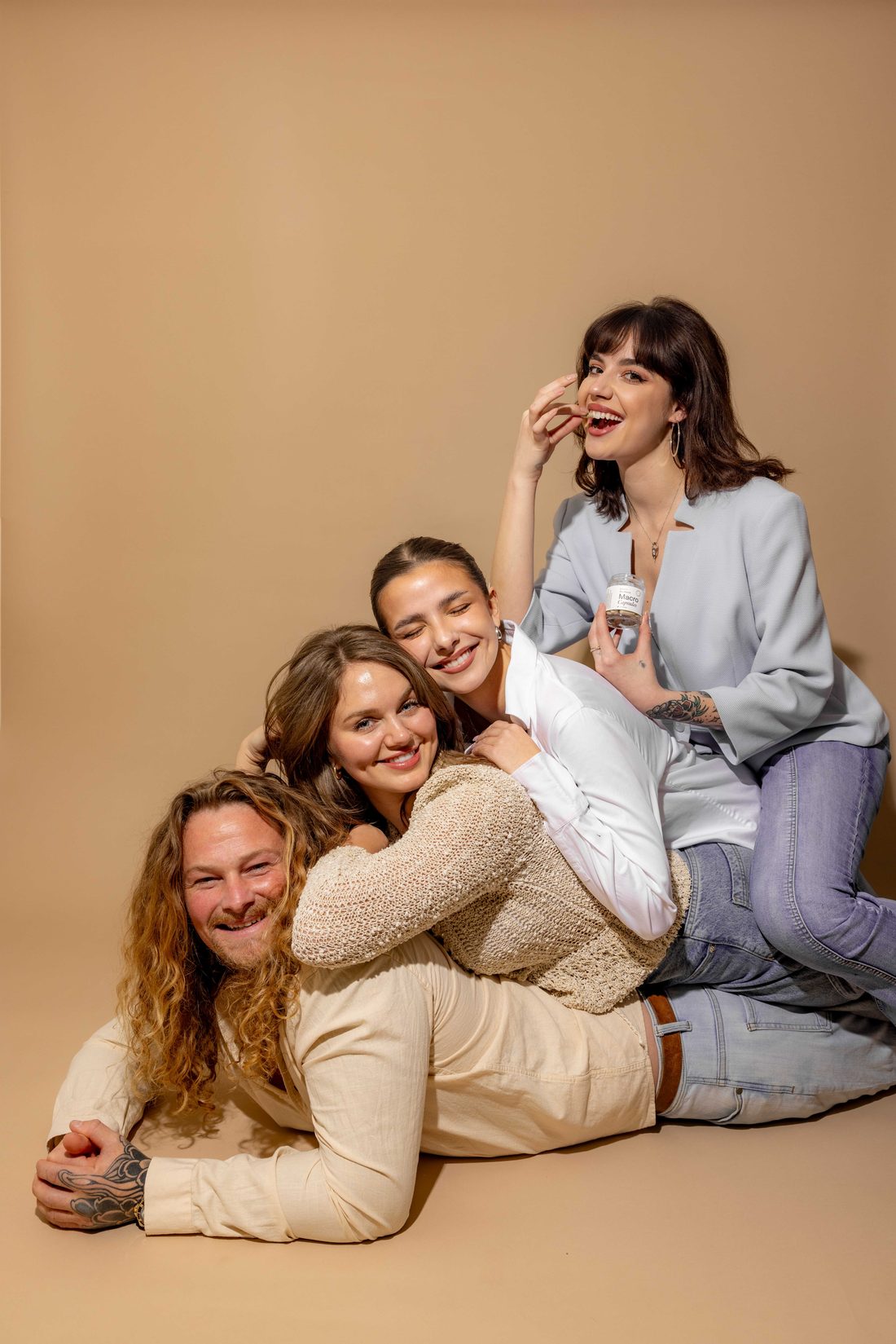 fall macrodose night in - Blog A group of friends piled together laughing on a warm cream backdrop