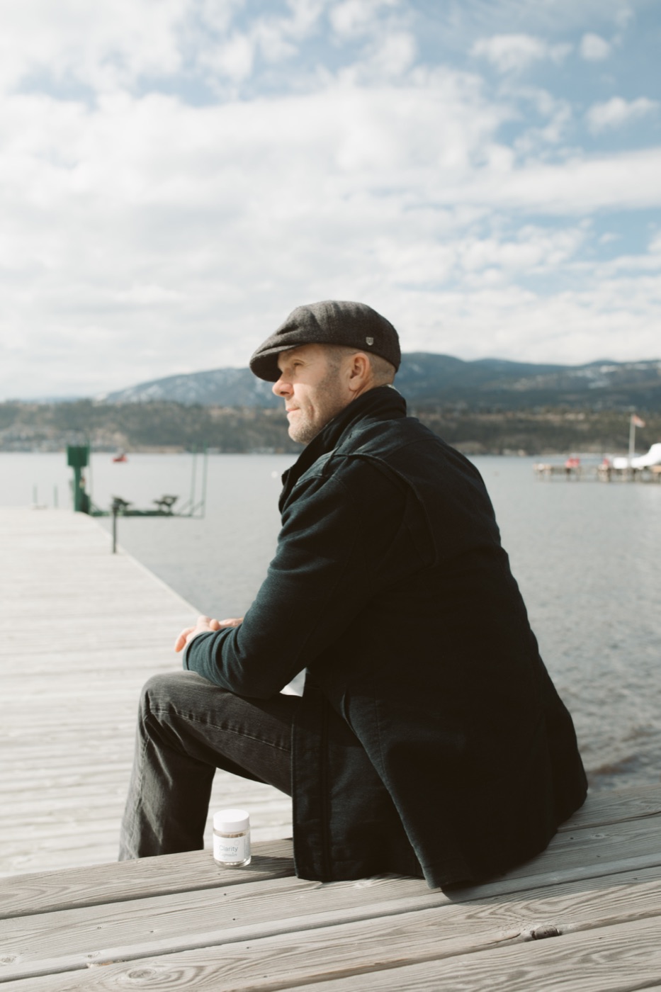 fifty plus man dock - Blog A man in a flat cap sitting alone on a lakeside dock in Kelowna with a jar of capsules beside him