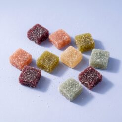 magic gummies scatter - Magic Gummies cubes scattered across a periwinkle surface with loose sanding sugar